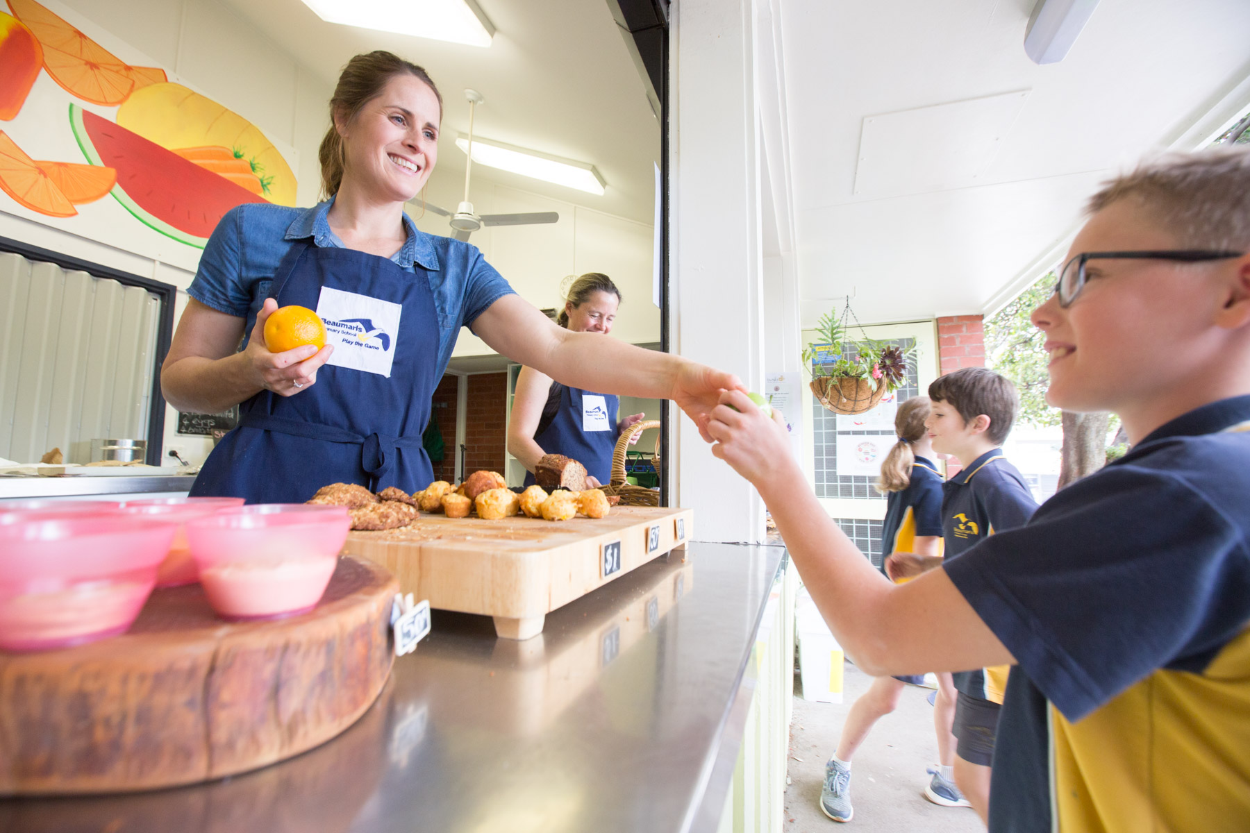 Canteen staff giving fruit to a student at the canteen
