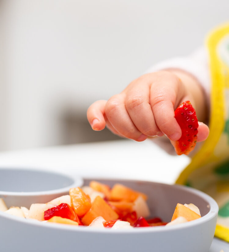 child with bowl of fruit