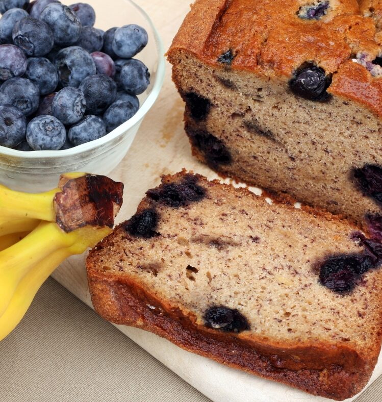 banana bread load sliced next to fresh blueberry and banana