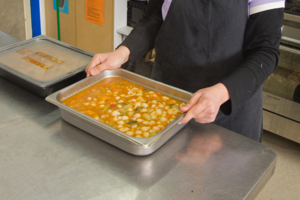 Cook in kitchen preparing soup