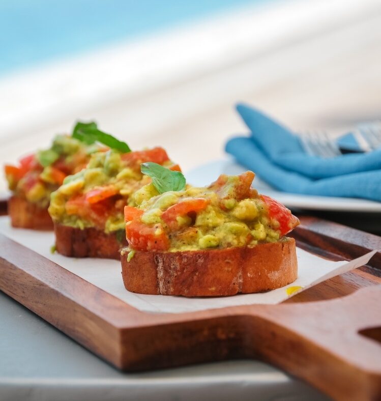 Avocado smash bruschetta on a wooden board