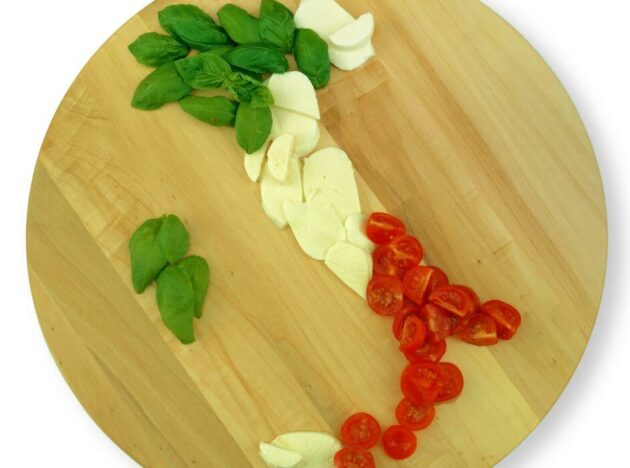 a board arranged with basil, garlic and tomatoes