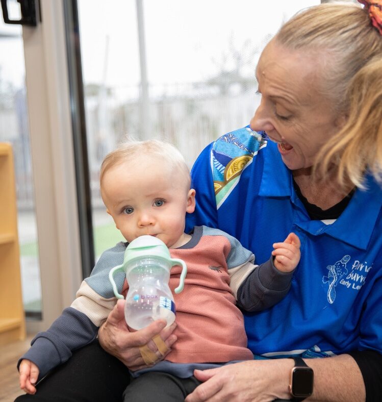 Carer holding baby while feeding with a bottle