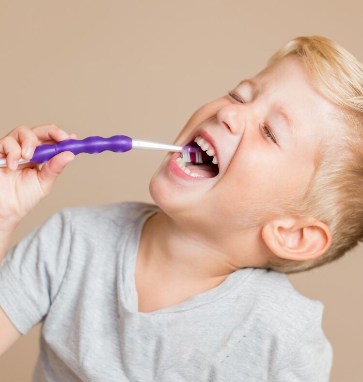 A young child smiling and brushing their teeth