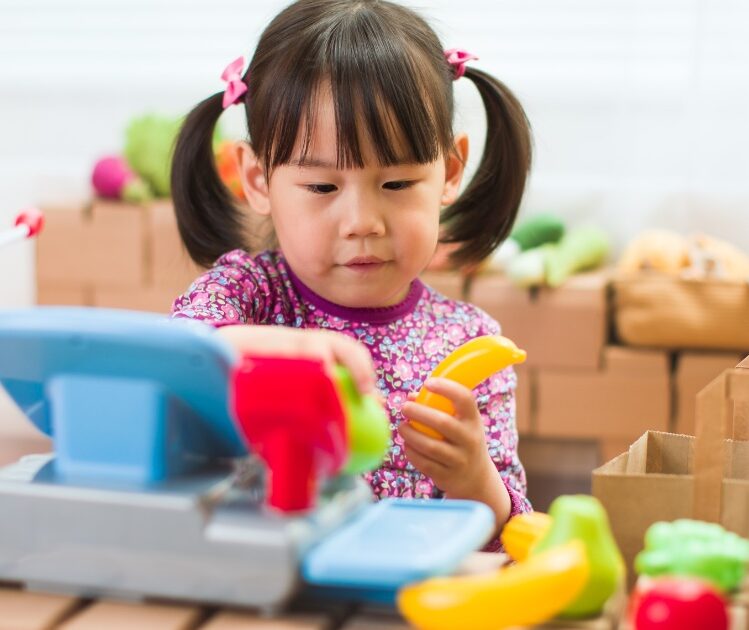 Young girl playing with plastic fruit toys