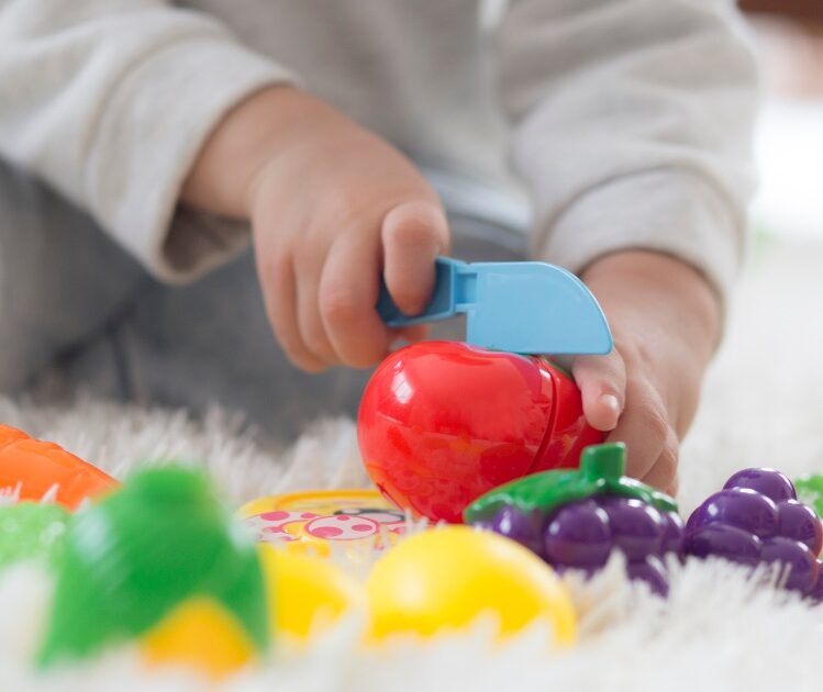 Child cutting plastic fruit toys with plastic knife