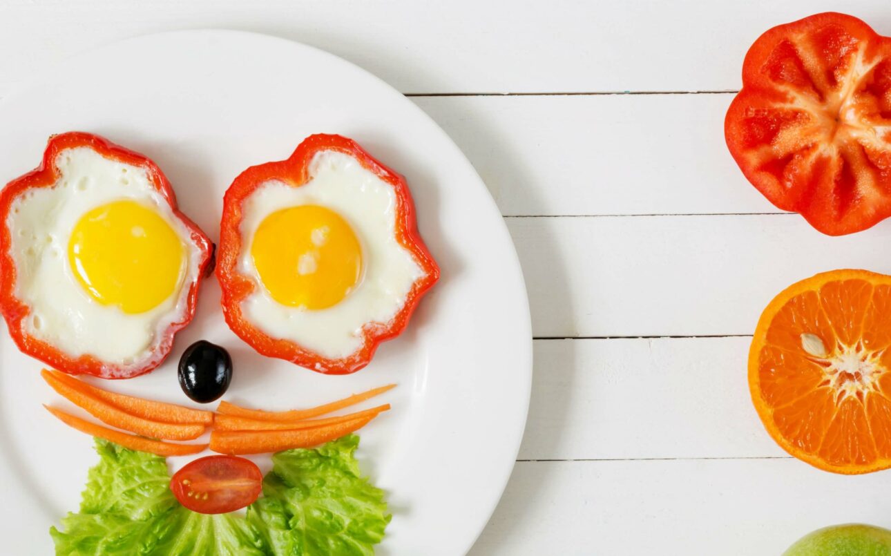 a face made out of vegetables and fried eggs on a plate