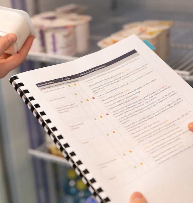 Hands holding a guideline booklet in front of a fridge