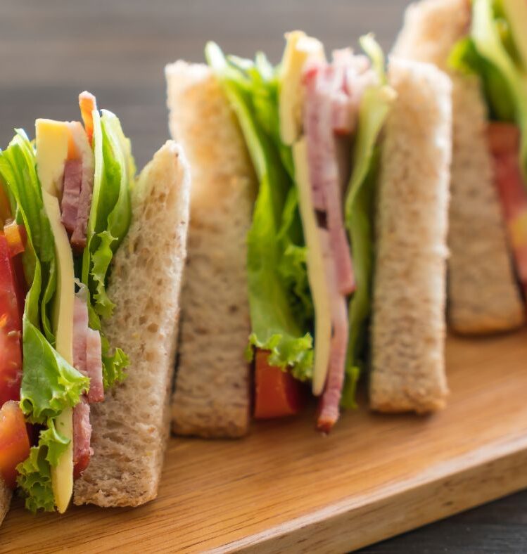 Ham, cheese and salad sandwiches on wooden board