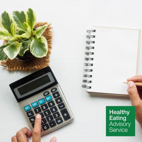 Calculator, notepad and plant on desk