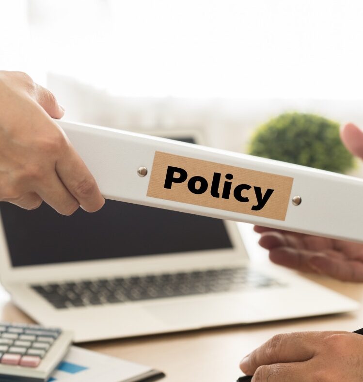 Man passing a folder labelled policy to another man