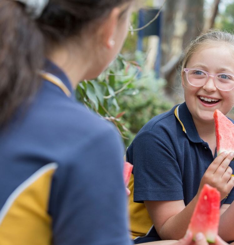 Two school children eating watermelon