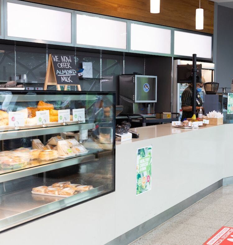Counter of a cafe with a glass display case containing sandwiches and baked goods