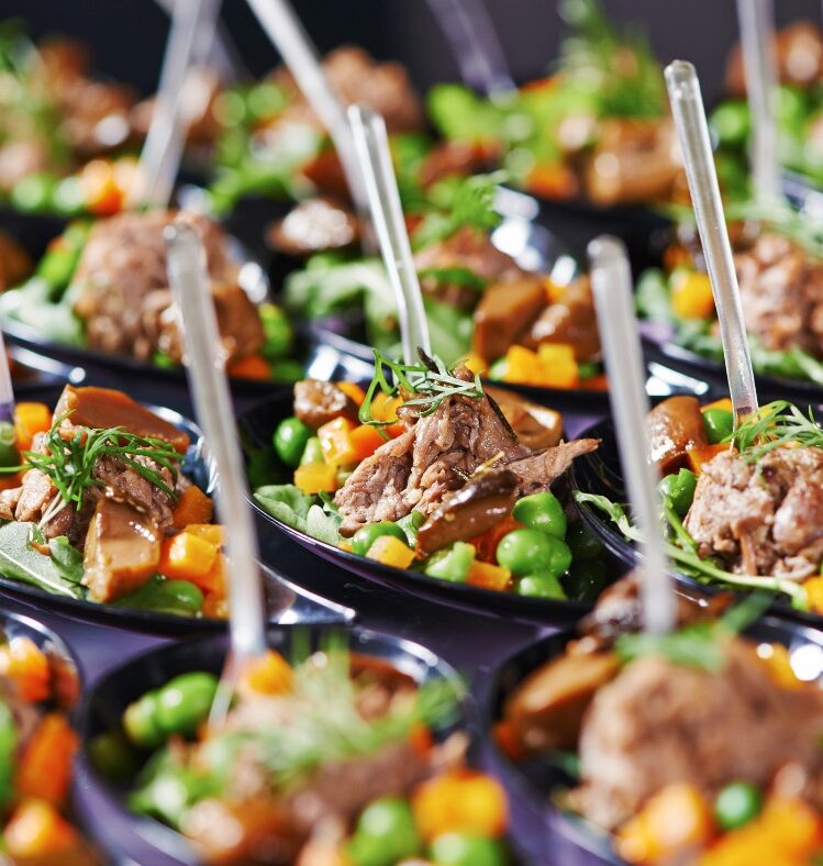 numerous small dishes of meat and vegetables with plastic spoons in each