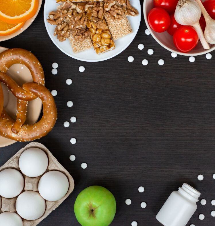 Pretzels, fruit, vegetables and eggs in bowls on a brown table