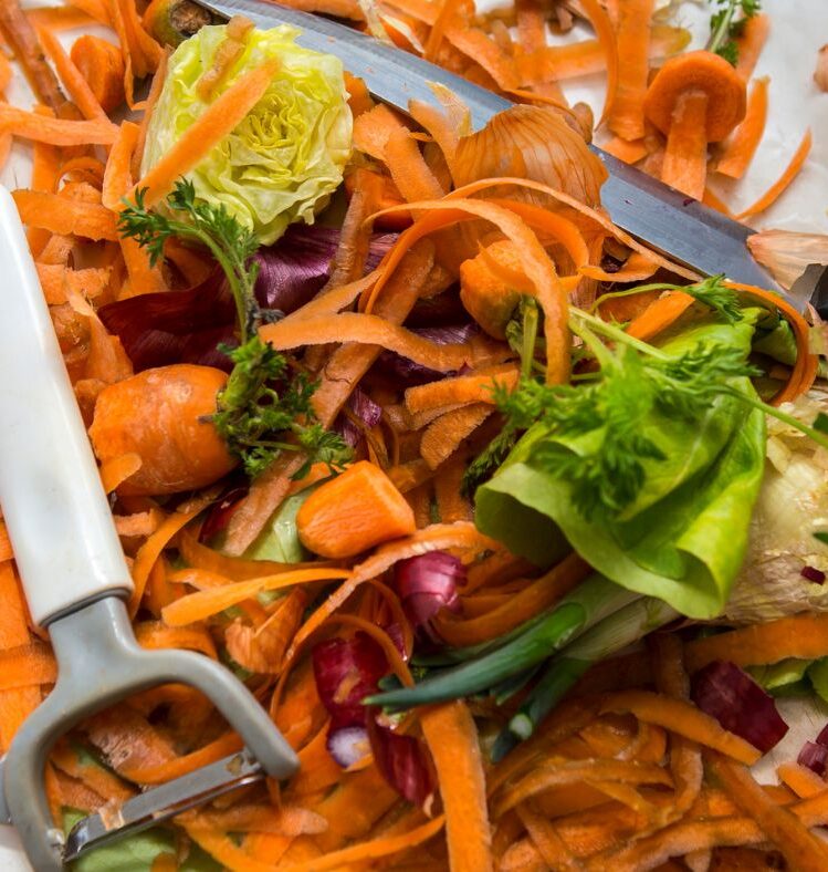 A pile of vegetable scraps with a vegetable peeler