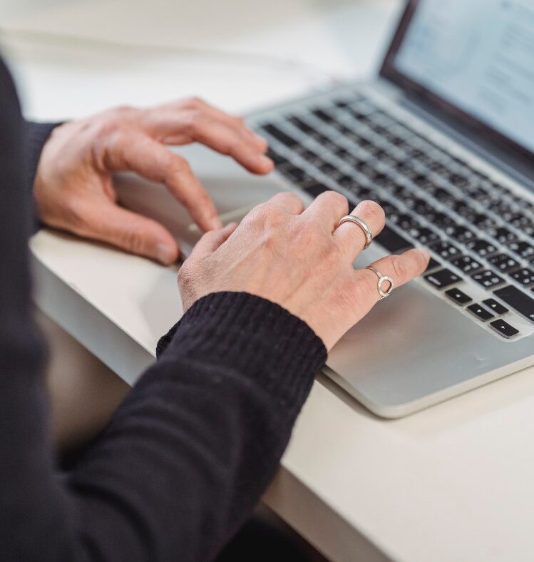 Woman with two rings on her right hand using a laptop