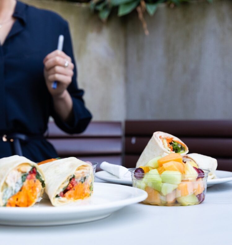 Wrap on a plate next to a tub of fruit salad