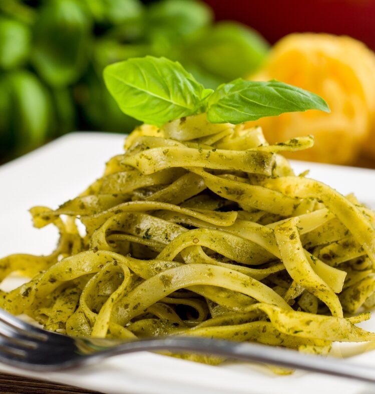 A serving of basil pesto pasta topped with a sprig of basil