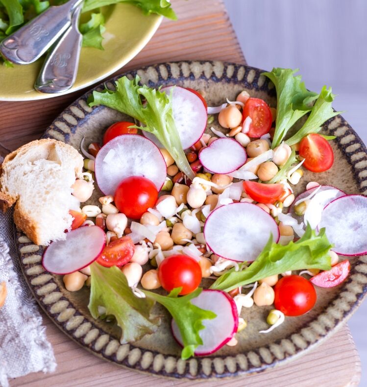 bean, tomato and radish salad on a plate served next to a slice of bread