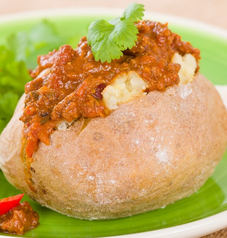 a baked potato cut across vertically topped with lamb chilli