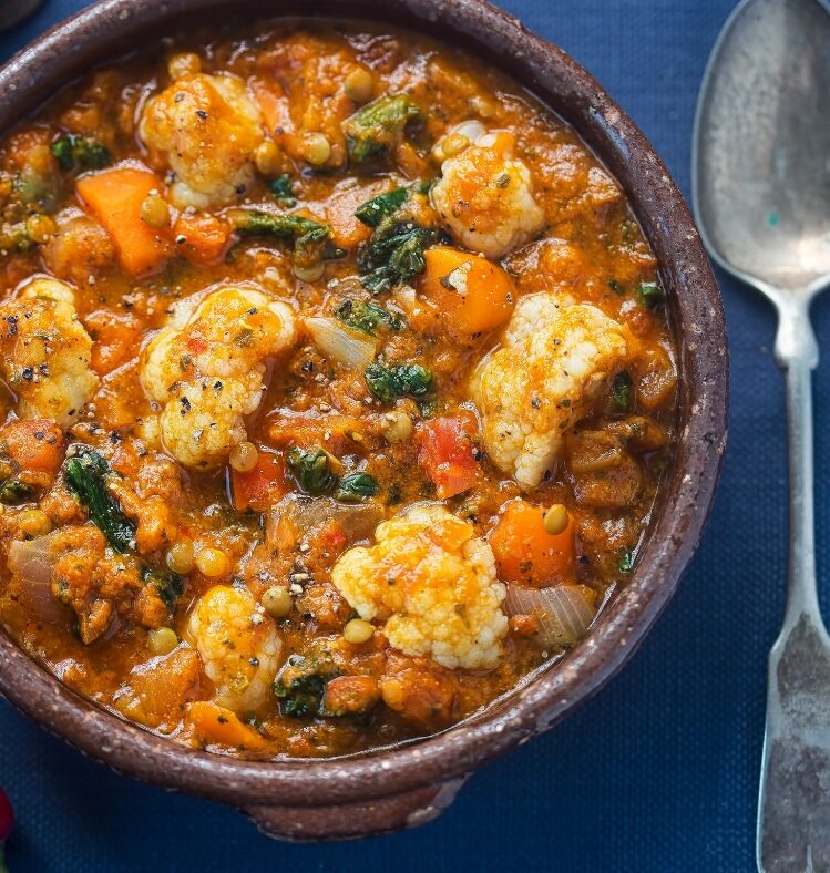a bowl of cauliflower dahl and rice next to a spoon