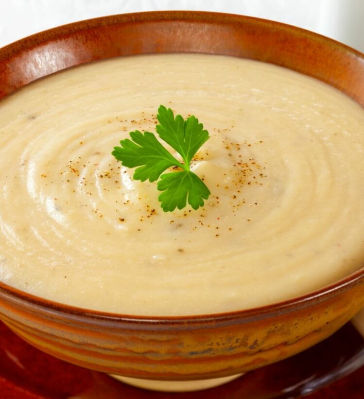 creamy cauliflower soup topped with a sprig of parsley