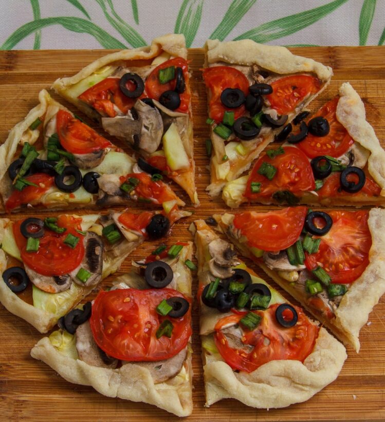 Gluten and dairy free pizza topped with tomatoes, olives and mushrooms