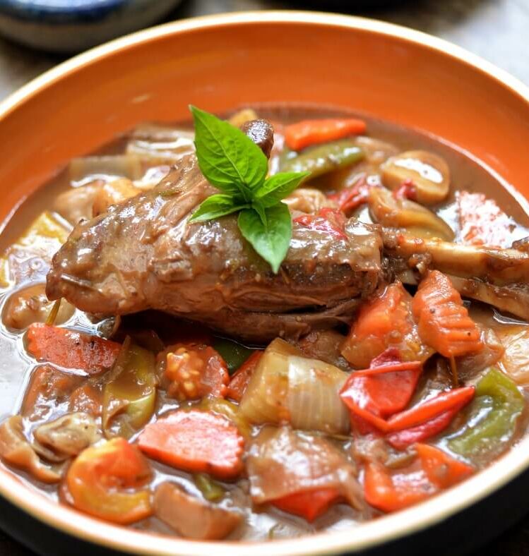 slow braised lamb shoulder with various vegetables garnished with herbs