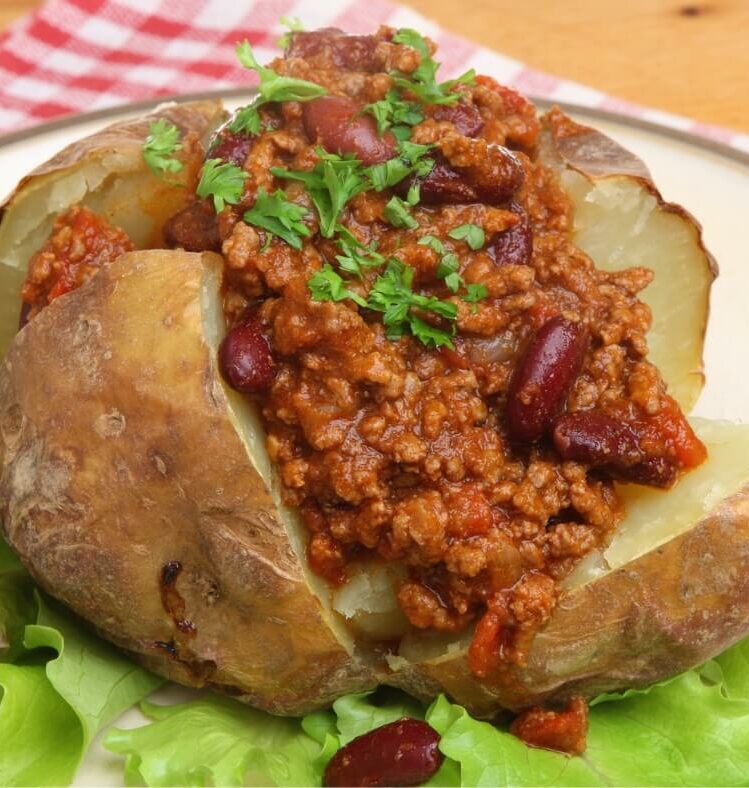 a baked potato cut open in quarters topped with Mexican beef and herbs