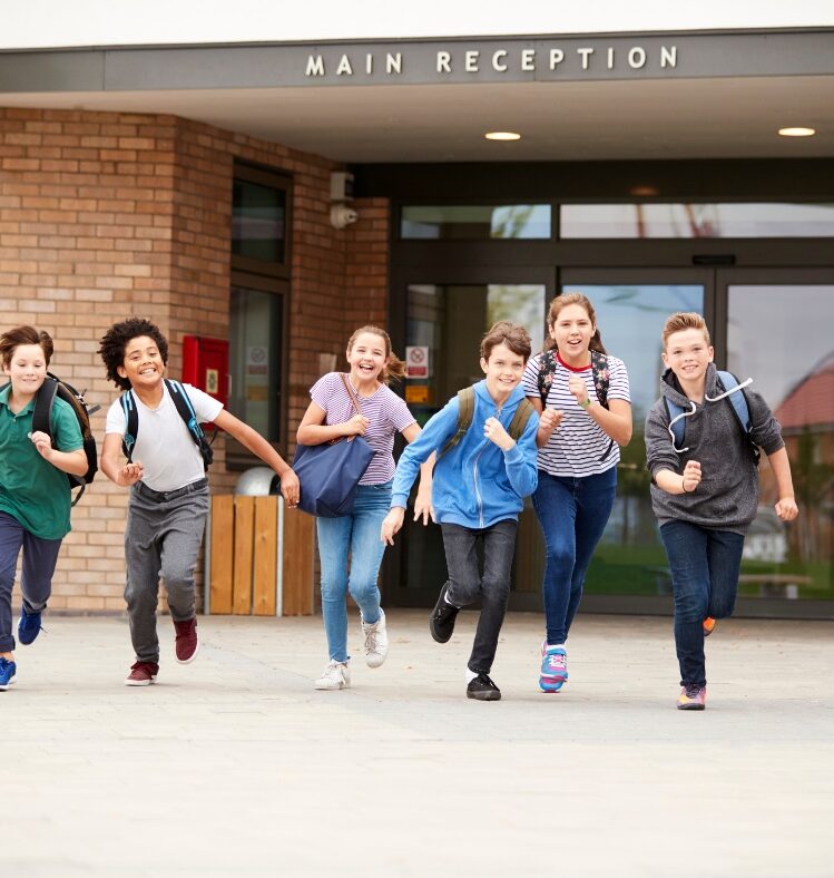 School children running toward camera smiling