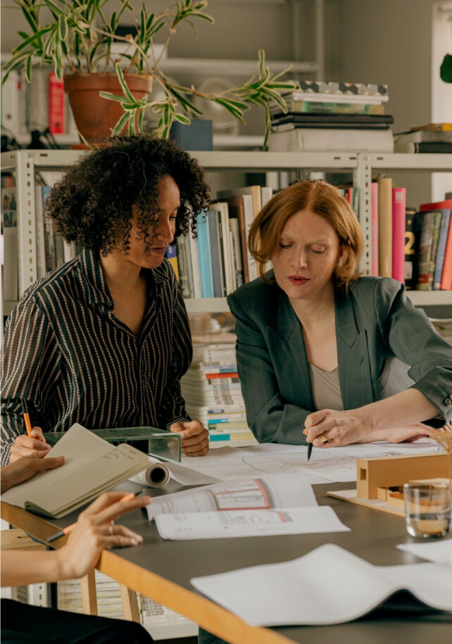 Two people sitting at a table discussing paperwork