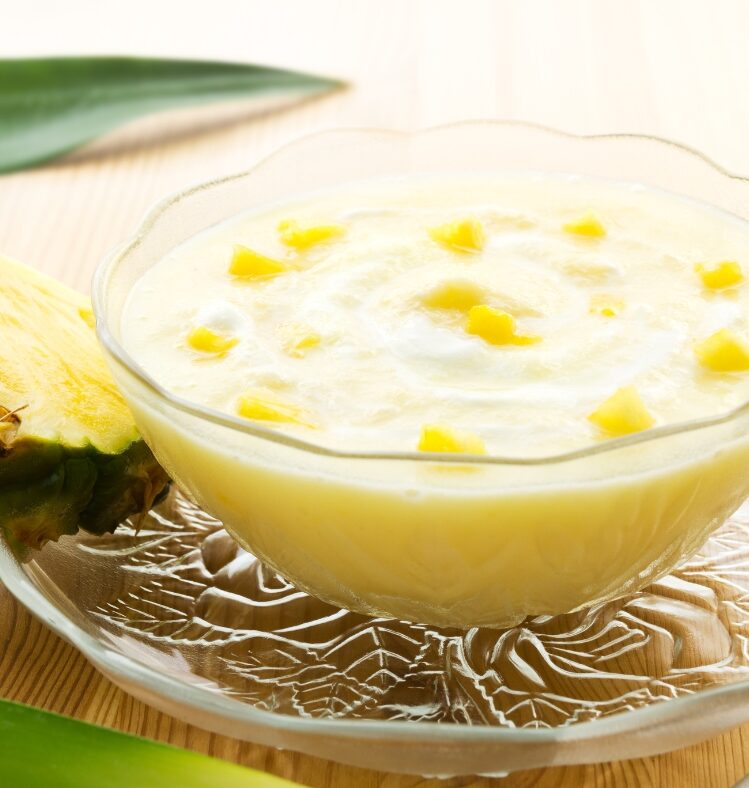 a bowl of pineapple yogurt dip next to a slice of pineapple