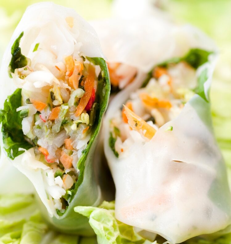 Two rice paper rolls filled with vegetables and sitting on lettuce