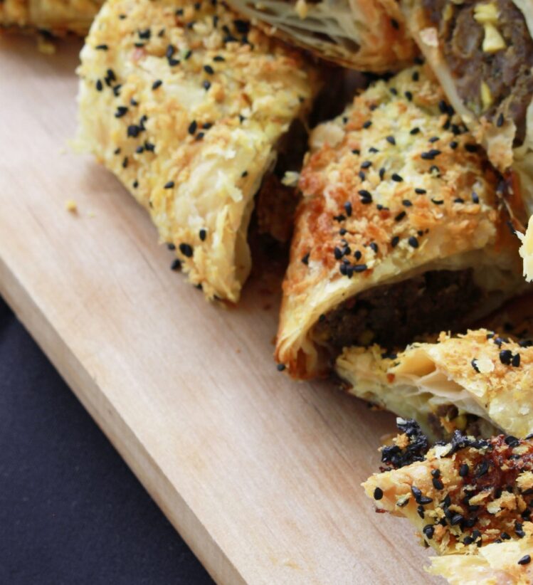 Small sausage roll pieces stacked roughly on a chopping board