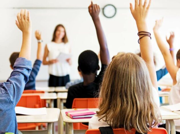 students raising their hands to answer a question