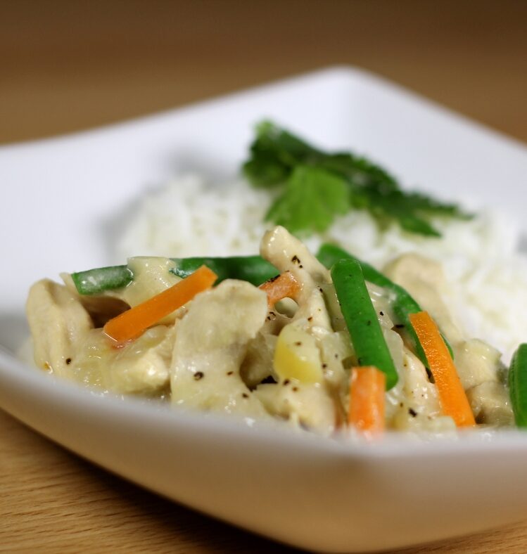White plate with Thai green chicken curry on it