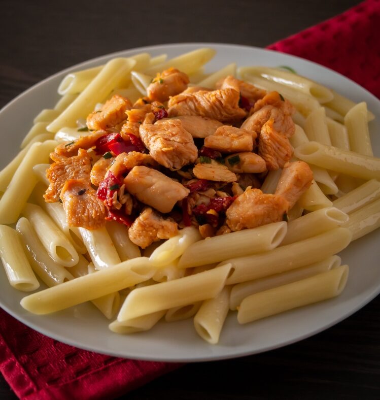 Pasta with tuscan chicken sauce on a white plate