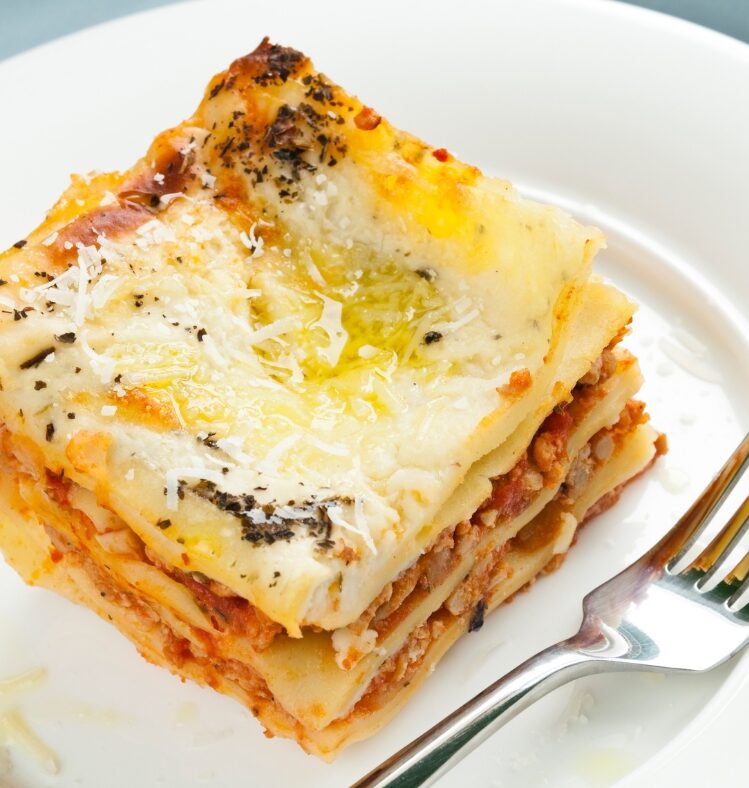 a slice of vegetarian lasagne on a white plate with a fork