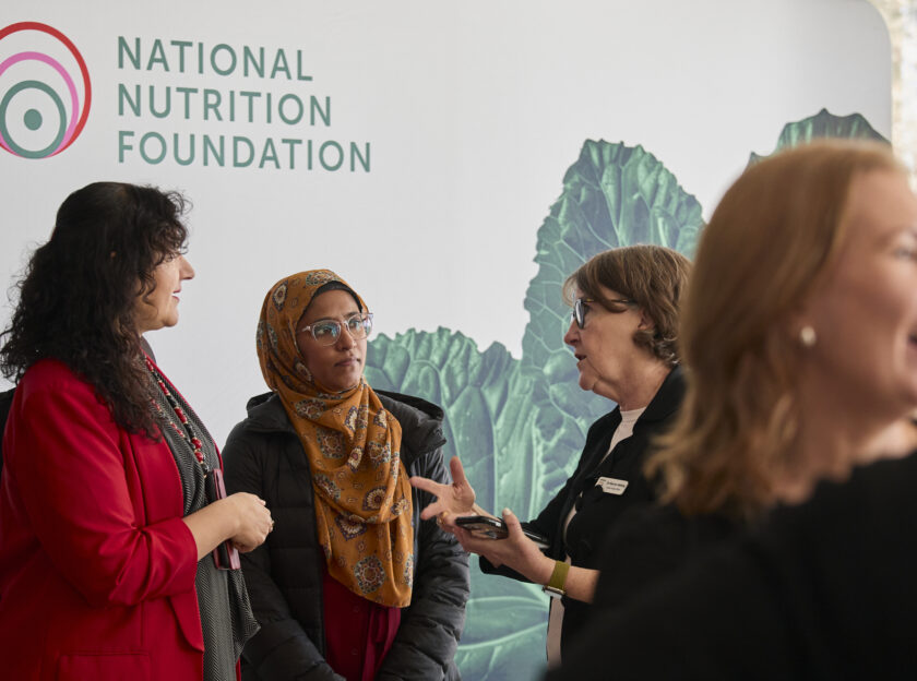 People in conversation with the National Nutrition Foundation backdrop in the background